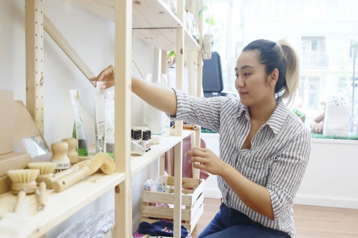 Female business owner stocking shelves in her business