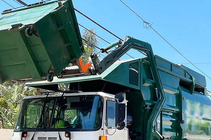 Garbage truck lifting a dumpster.